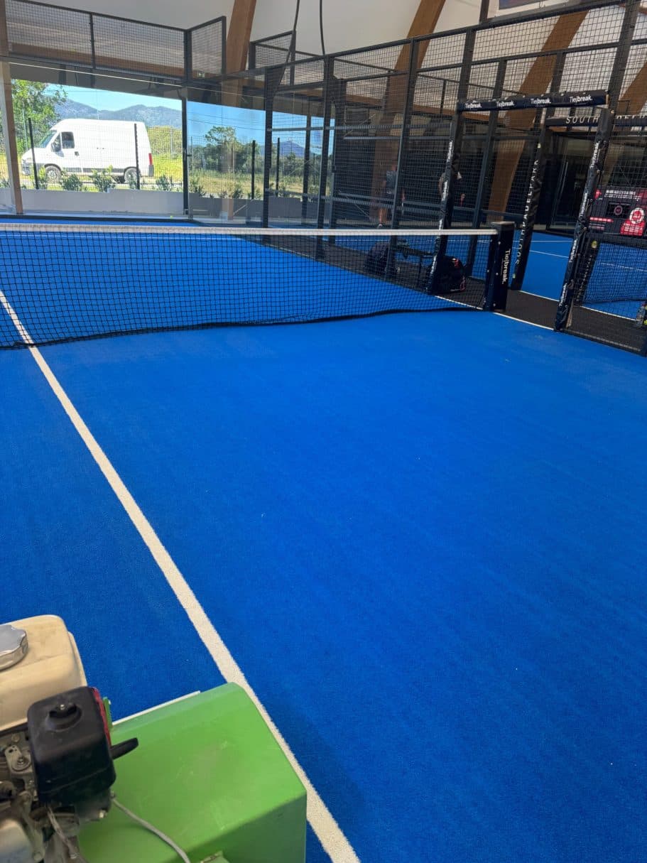 Machine de décompactage sur la moquette bleue d'un club de padel