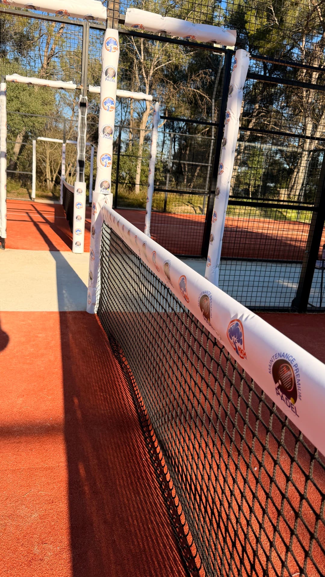 Protections de sortie de piste installées sur un court de padel en terre battue