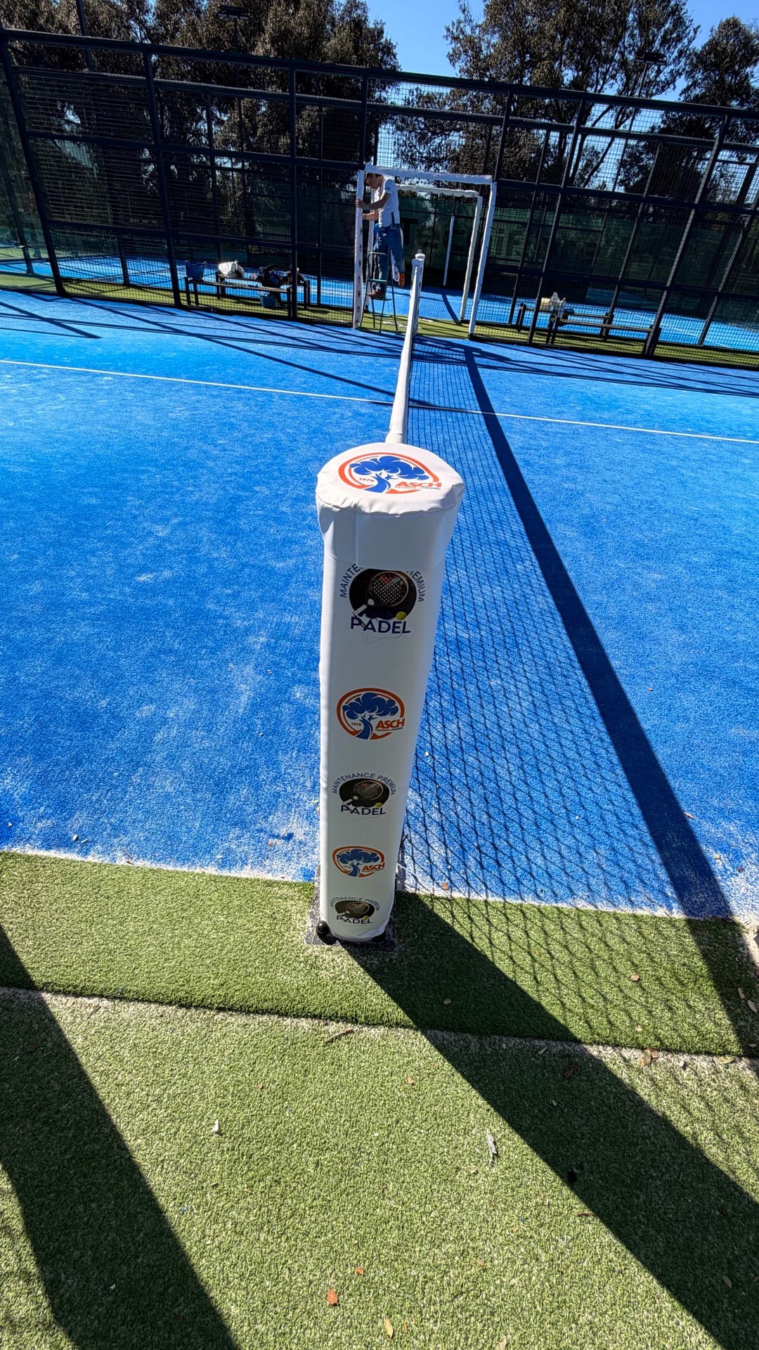 Vue d'ensemble des protections de poteaux blanches floquées sur un court de padel bleu
